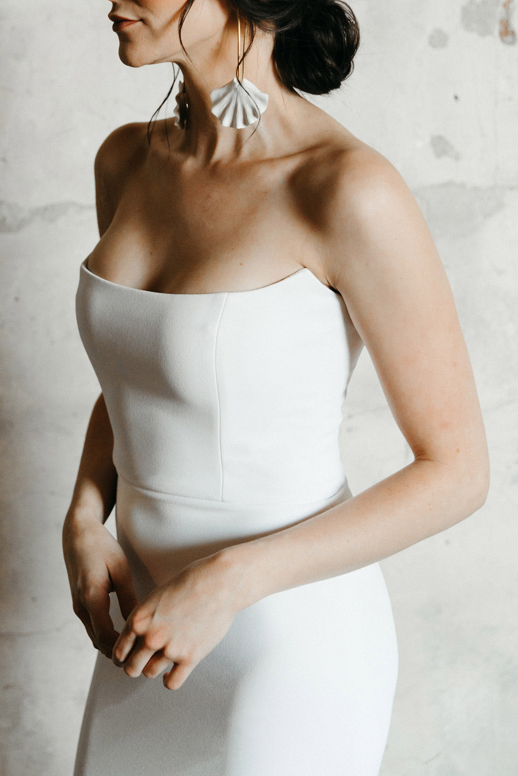 Bridal model wearing romantic updo, statement earrings, and strapless scoop neckline wedding dress.