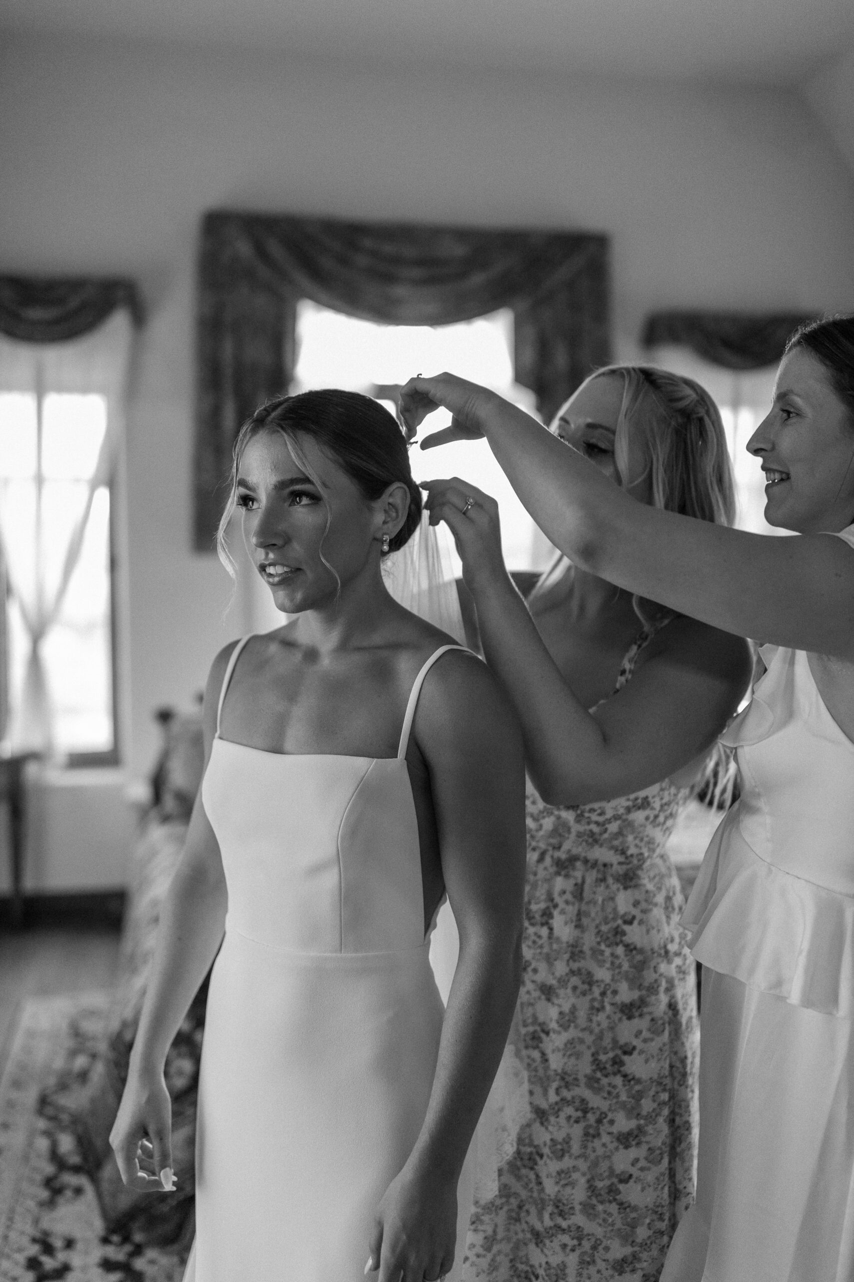 Black and white photos of hanging wedding dress and bride getting ready