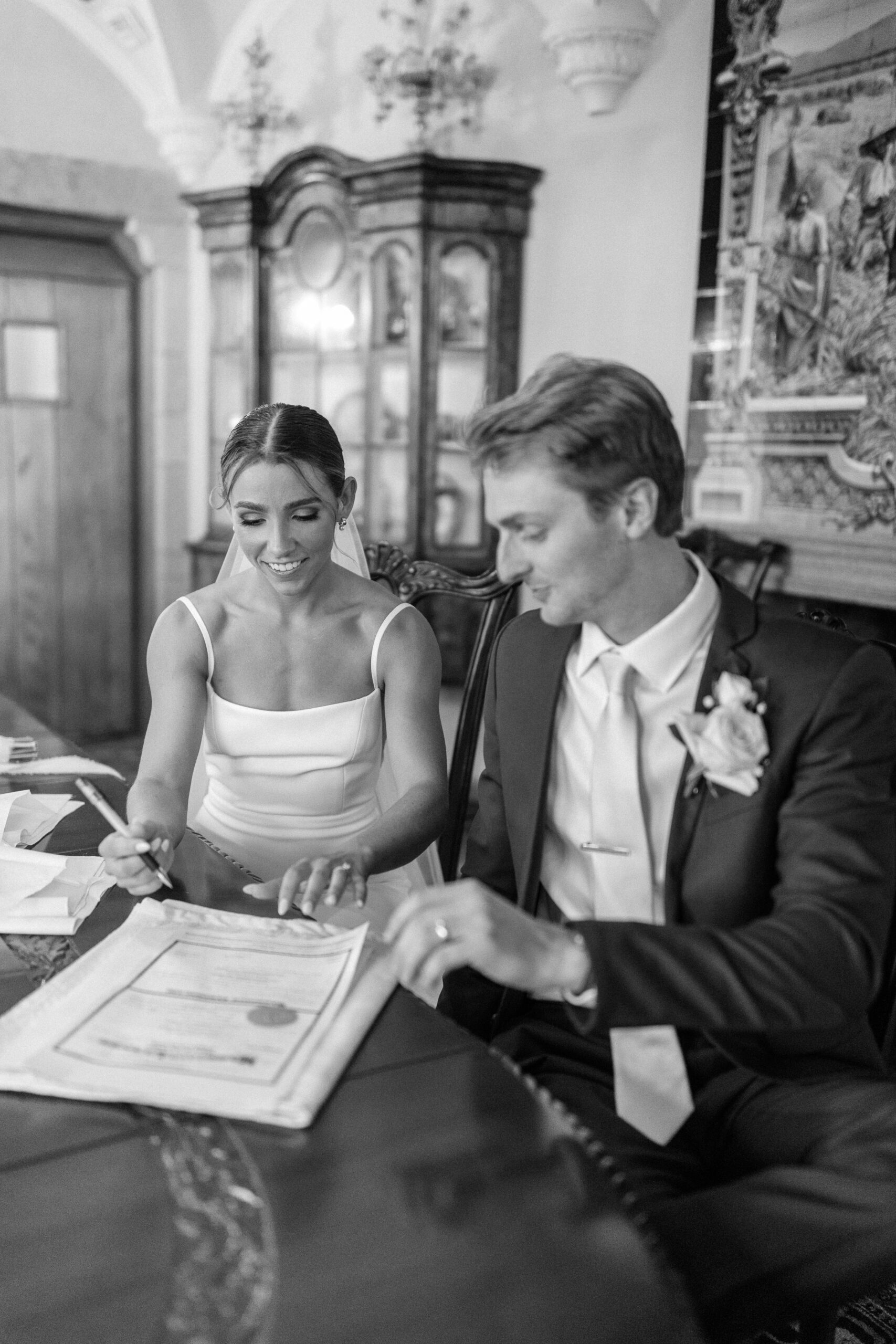 Bride and groom leaning over table signing their marriage certificate
