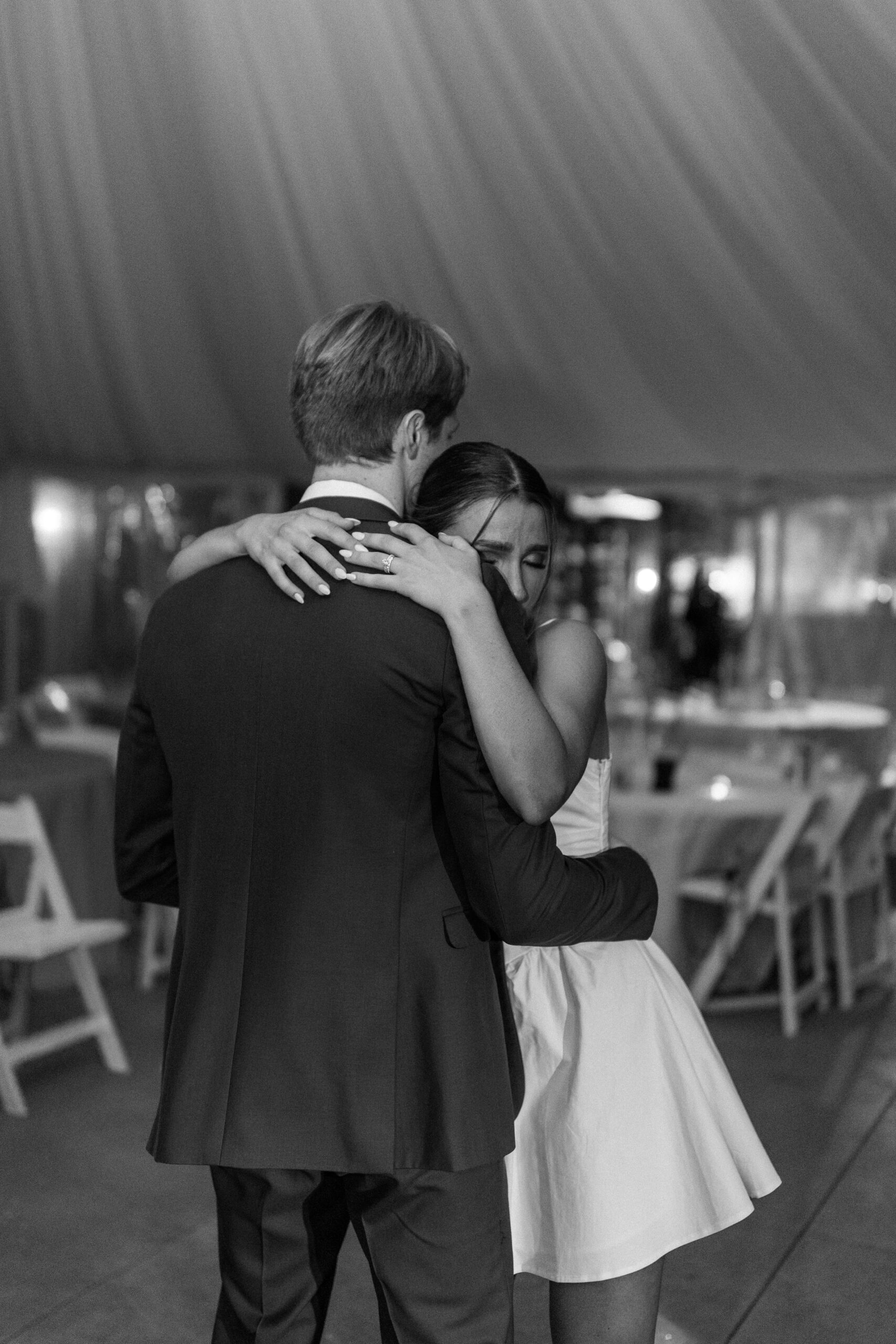 Black and white photo of bride and groom in empty reception tent dancing